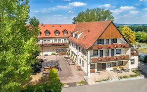 A traditional European-style building with a courtyard, multiple balconies with flower boxes, and outdoor seating areas.