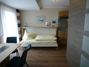 Une chambre comprenant un lit, un bureau et une kitchenette.