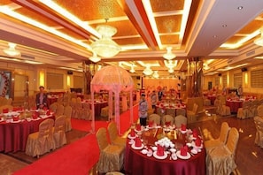 A banquet hall with round tables, chairs, and a red carpet. - Hongdu Hotel (Xingning)