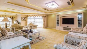 A spacious living room with a large TV, comfortable seating, and a decorative ceiling. - Hongdu Hotel (Xingning)
