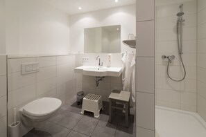 Driepersoonskamer | Badkamer | Een douche, een haardroger, handdoeken, zeep