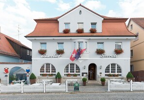 Il s’agit d’un bâtiment européen traditionnel, caractérisé par une façade blanche, un toit recouvert de tuiles rouges et de nombreuses fenêtres.
