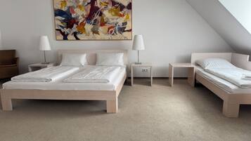 Un dormitorio moderno con una cama grande, dos mesitas de noche, una silla y un cuadro abstracto y colorido en la pared.