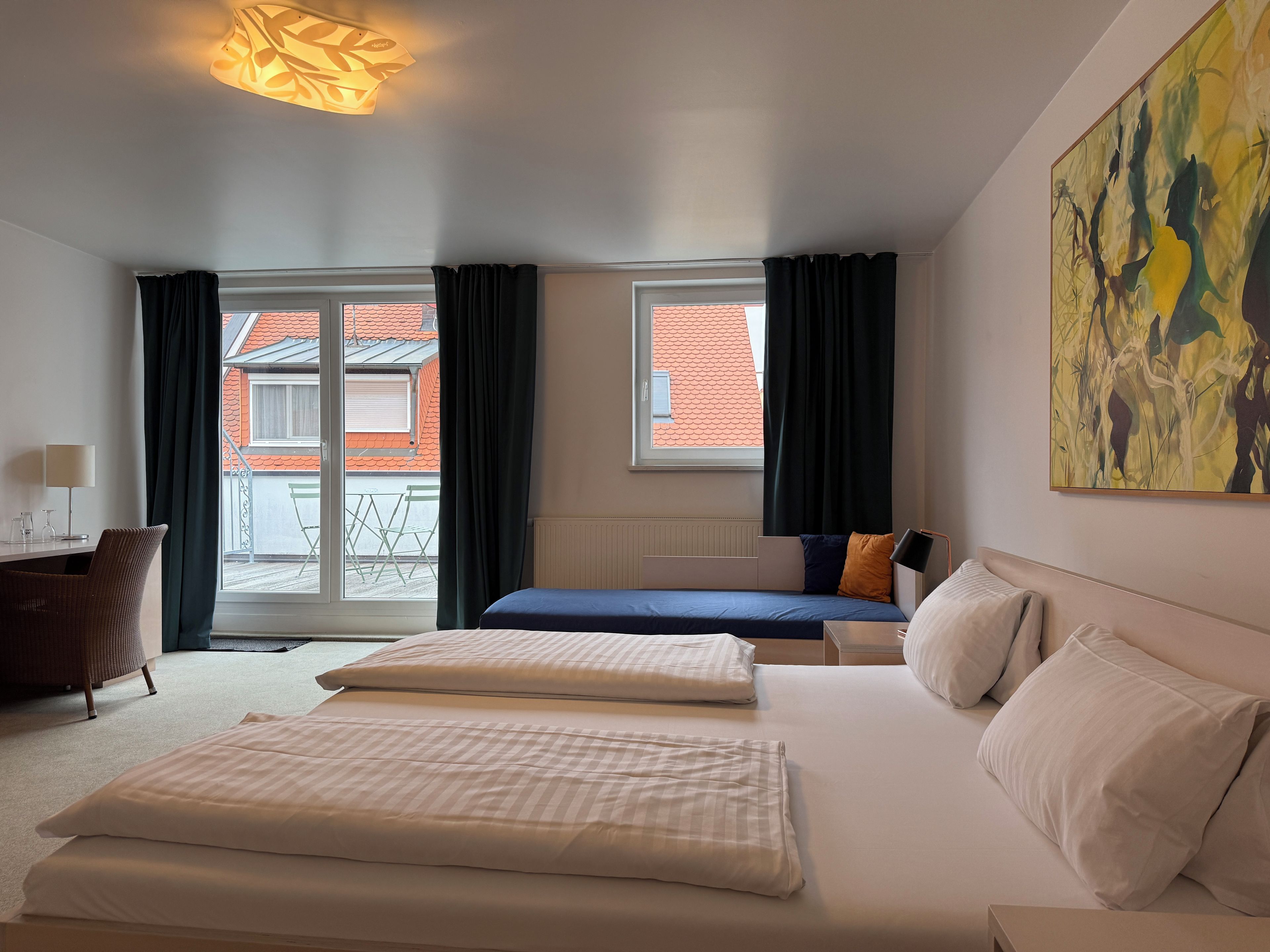 A hotel room with a bed, a desk, and a view of buildings outside.