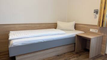 Een enkel bed met een houten hoofdeinde en een nachtkastje.