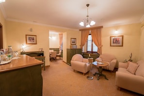 A hotel room with a dining area, a sofa set, a chandelier, and framed pictures on the walls. - Hotel Octarna (Kromeriz)