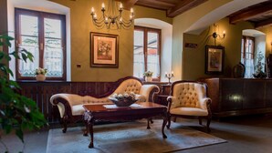 Una habitación tradicional con dos sillones tapizados, una mesa de centro de madera, una araña y cuadros enmarcados en las paredes.