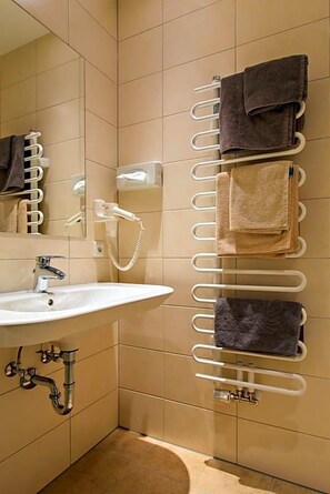 A bathroom with a white sink, a mirror, a towel rack, and a handheld showerhead.