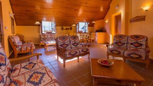 A cozy living room with wooden furniture, patterned cushions, and a tiled floor. - Casa Francho (Laspaules)