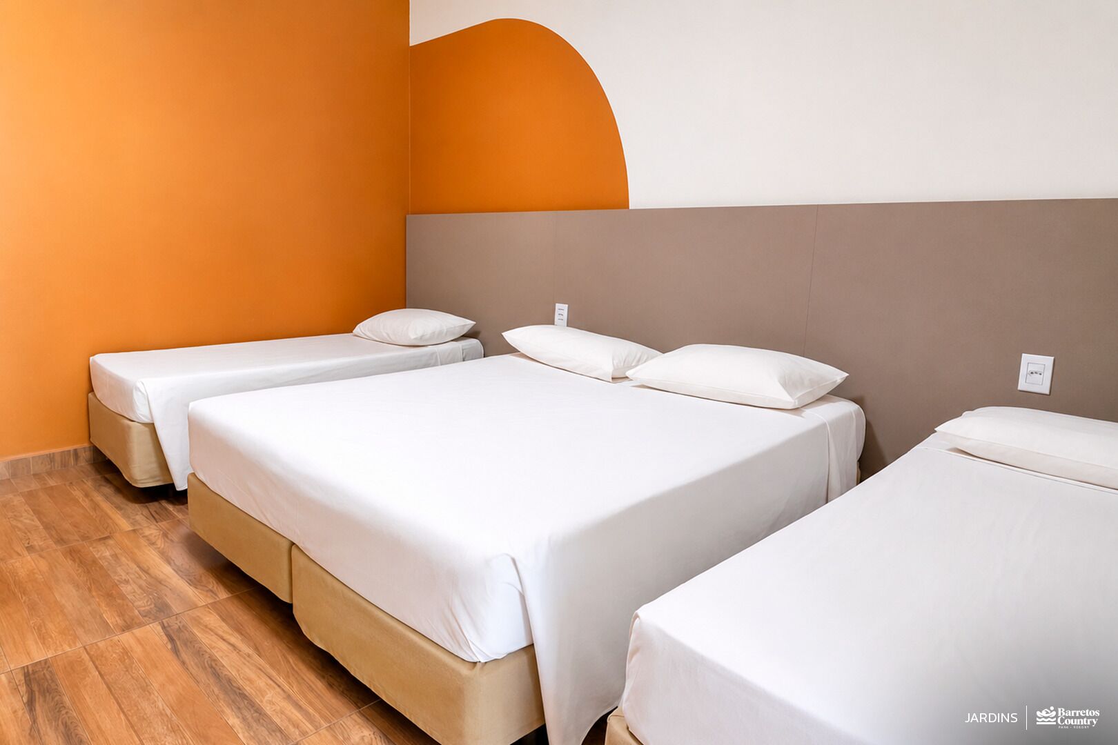 A hotel room with three beds, wooden flooring, and a modern design.