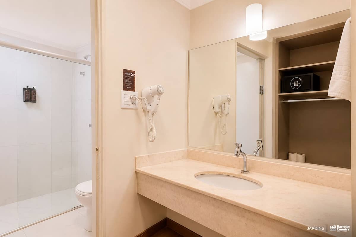 A bathroom with a sink, mirror, towel rack, and a shower area.