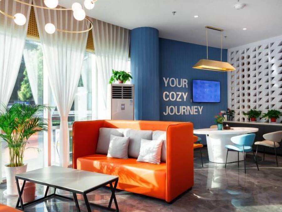 Eine moderne Hotelhalle mit einer Couch, Stühlen, einem Tisch, einem Fernseher und einer Wand mit einer Notiz.