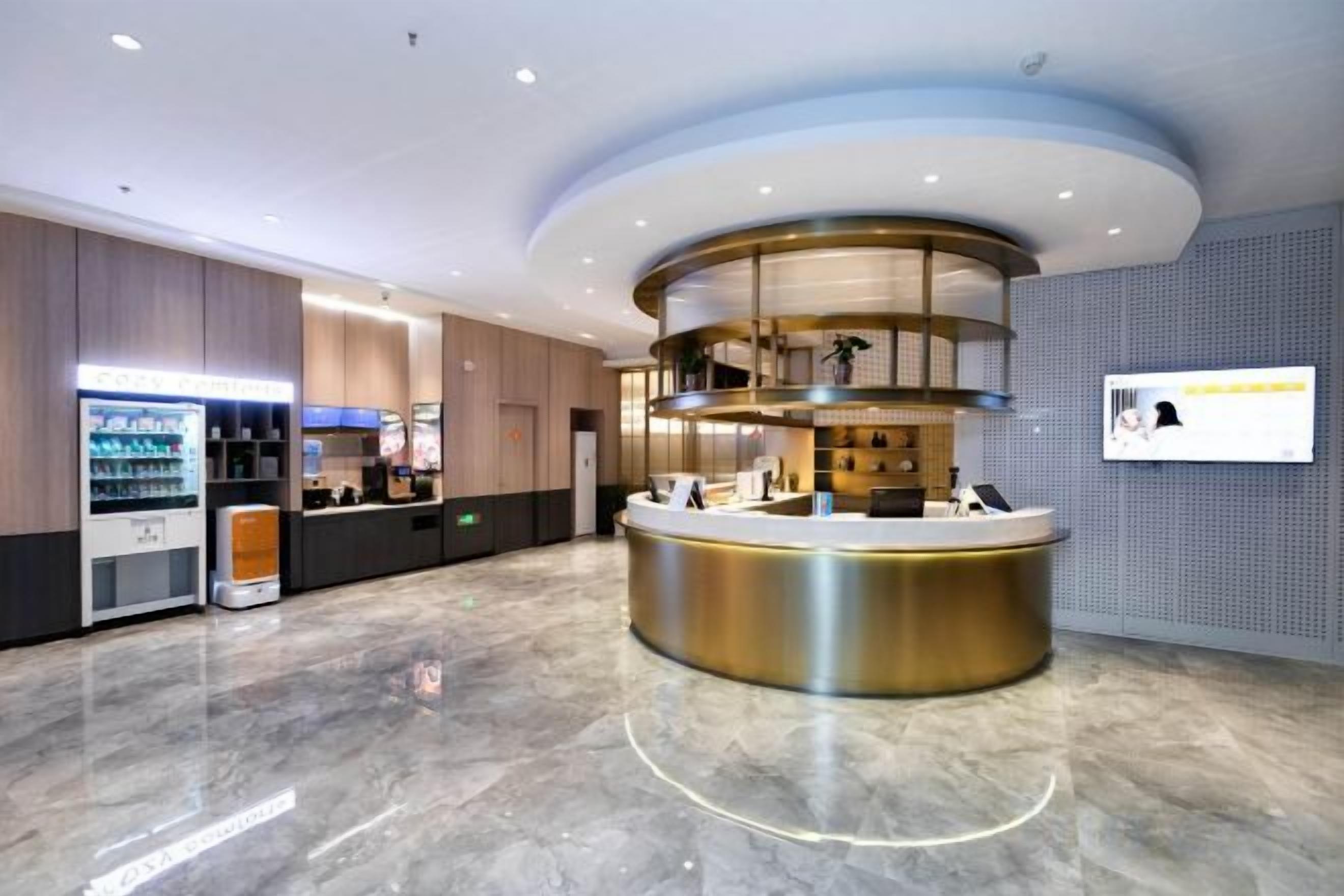 Un moderno vestíbulo de hotel con una recepción, una máquina de café y un área de estar.