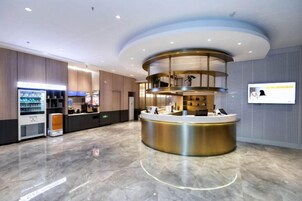 Un moderno vestíbulo de hotel con una recepción, una máquina de café y un área de estar.