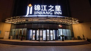 Außenansicht des Jinhua Inn mit markantem Eingang und beleuchteter Beschilderung.