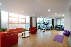 Una habitación amplia con un ventanal grande, una caminadora y equipo de ejercicio.