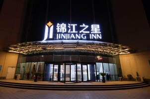 Una entrada de hotel con un cartel llamativo, puertas de vidrio y una fachada bien iluminada.