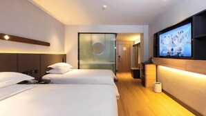Ein Hotelzimmer mit zwei Betten, einem Fernseher und einer Glaswand.