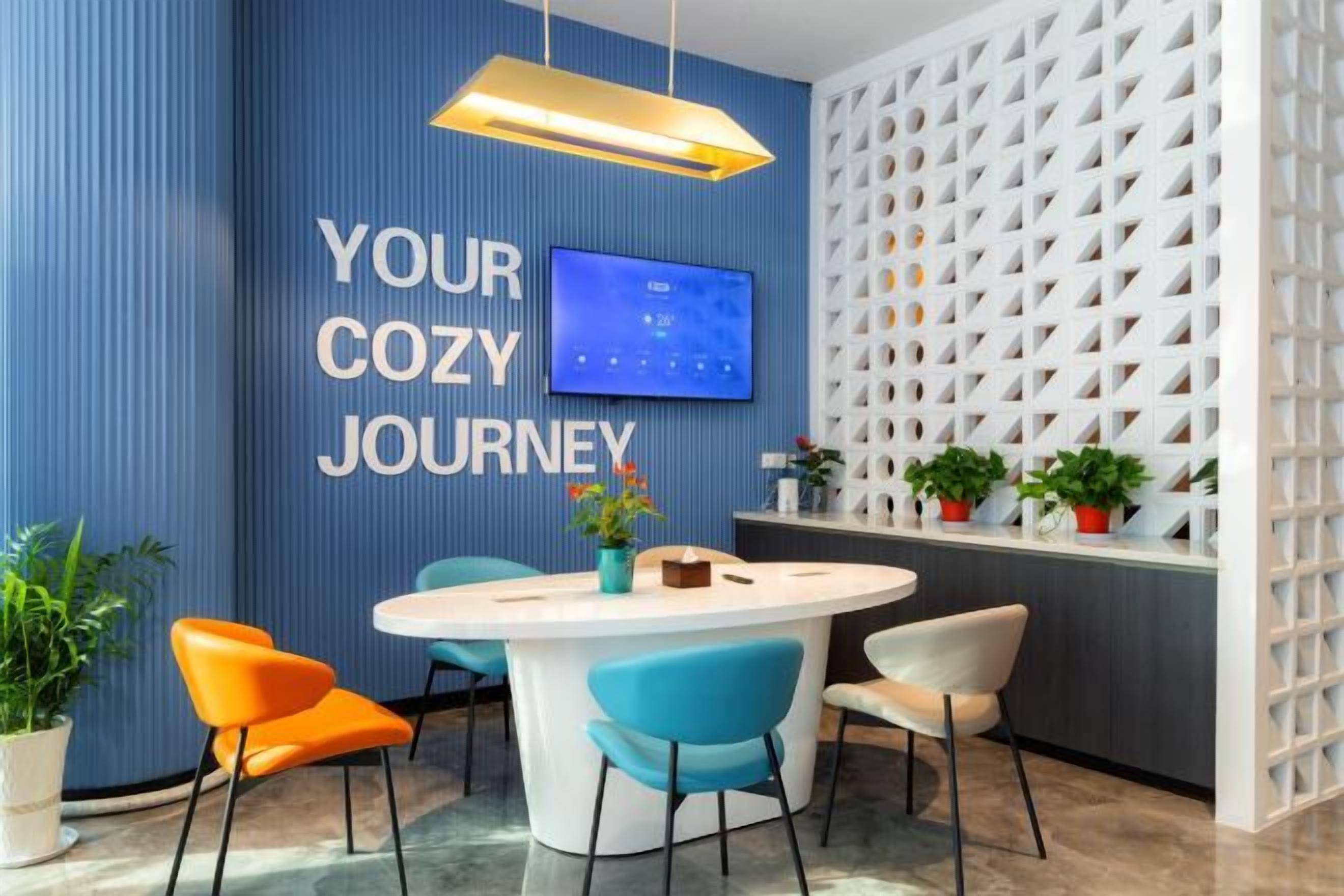 A modern room with a round table, chairs, a flat-screen TV, and a decorative wall with a geometric pattern.