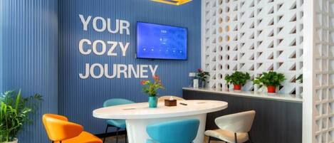 A modern room with a round table, chairs, a flat-screen TV, and a decorative wall with a geometric pattern.