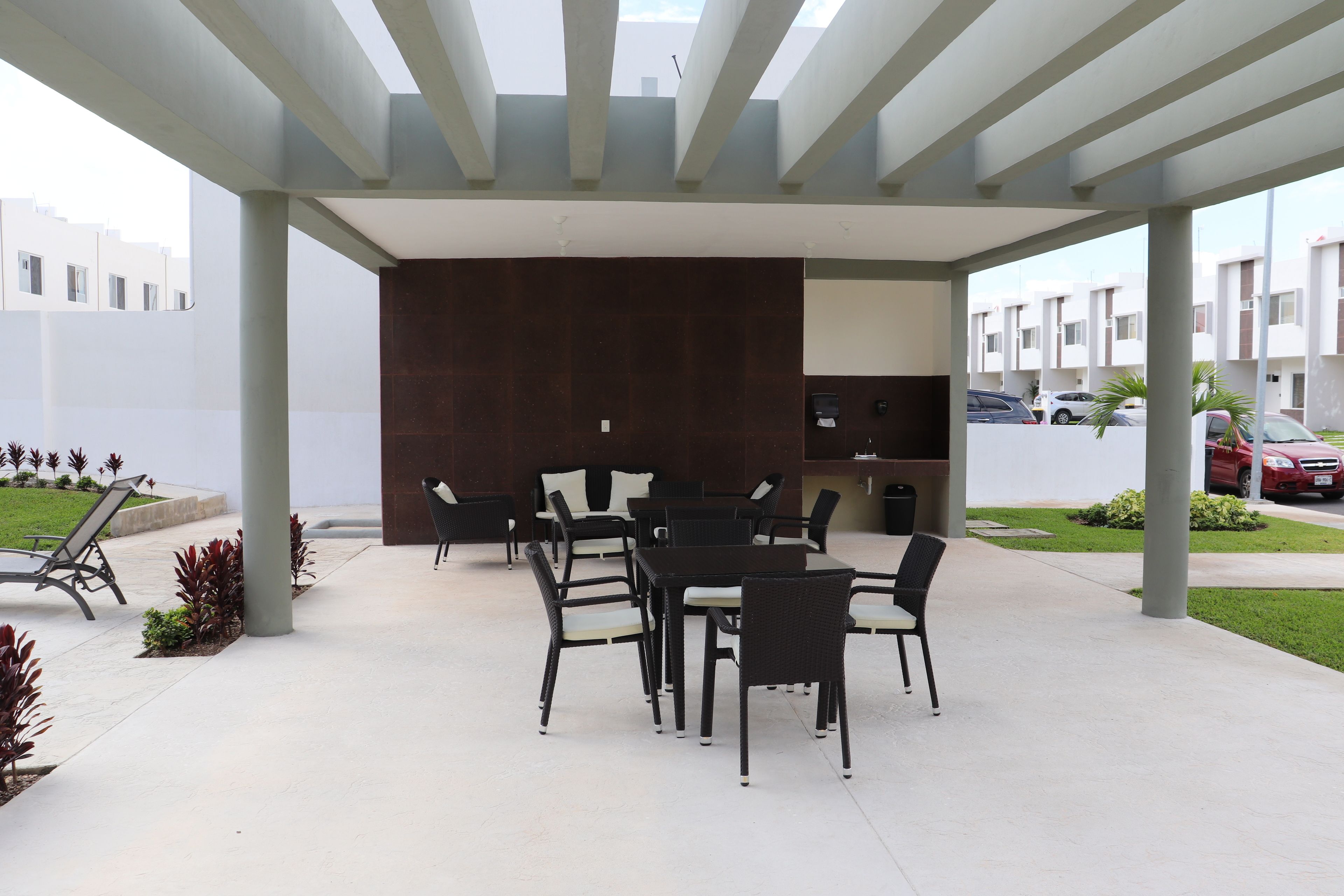 An outdoor patio with a covered seating area, a dark wall, and a view of a residential area.