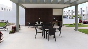 An outdoor patio with a covered seating area, a dark wall, and a view of a residential area. - Casa Vacacional Brothers House Economica (Playa del Carmen)