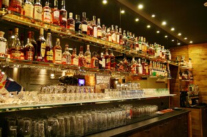 Un bar con numerosas estanterías llenas de botellas de licor y una gran variedad de vasos.