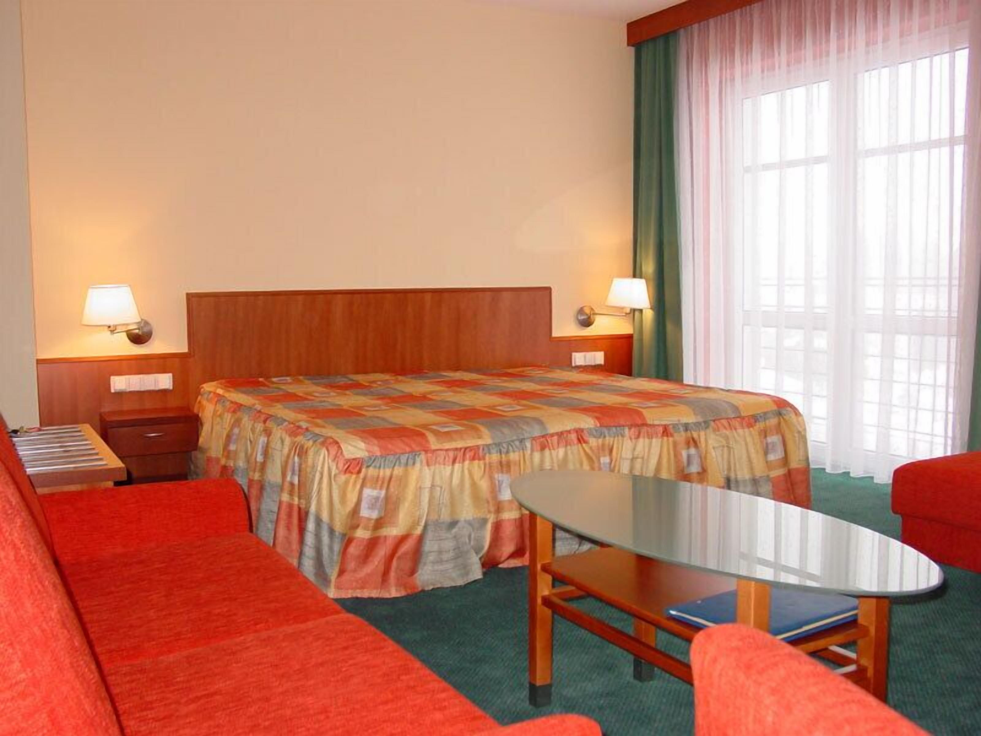 Ein Hotelzimmer mit Bett, Schreibtisch, Stuhl und einer Couch.