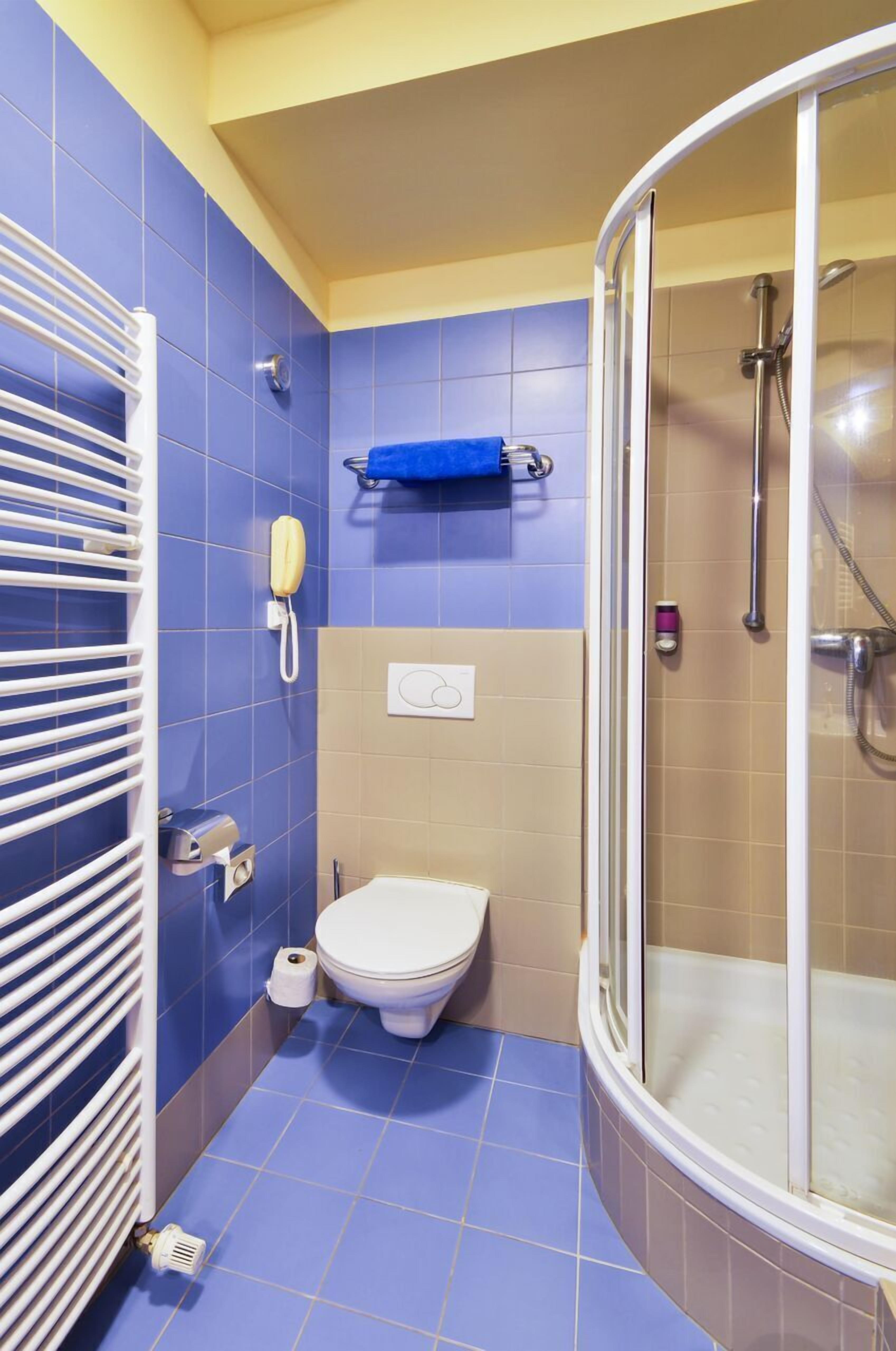 A bathroom with a toilet, a shower, a towel rack, and a hand dryer.
