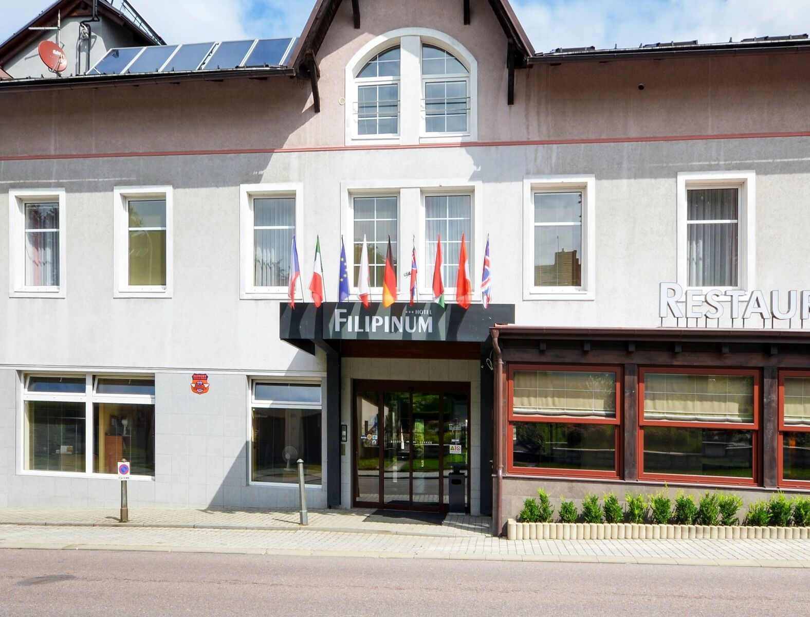 Un hôtel avec une enseigne indiquant « Filipinum » et plusieurs drapeaux.