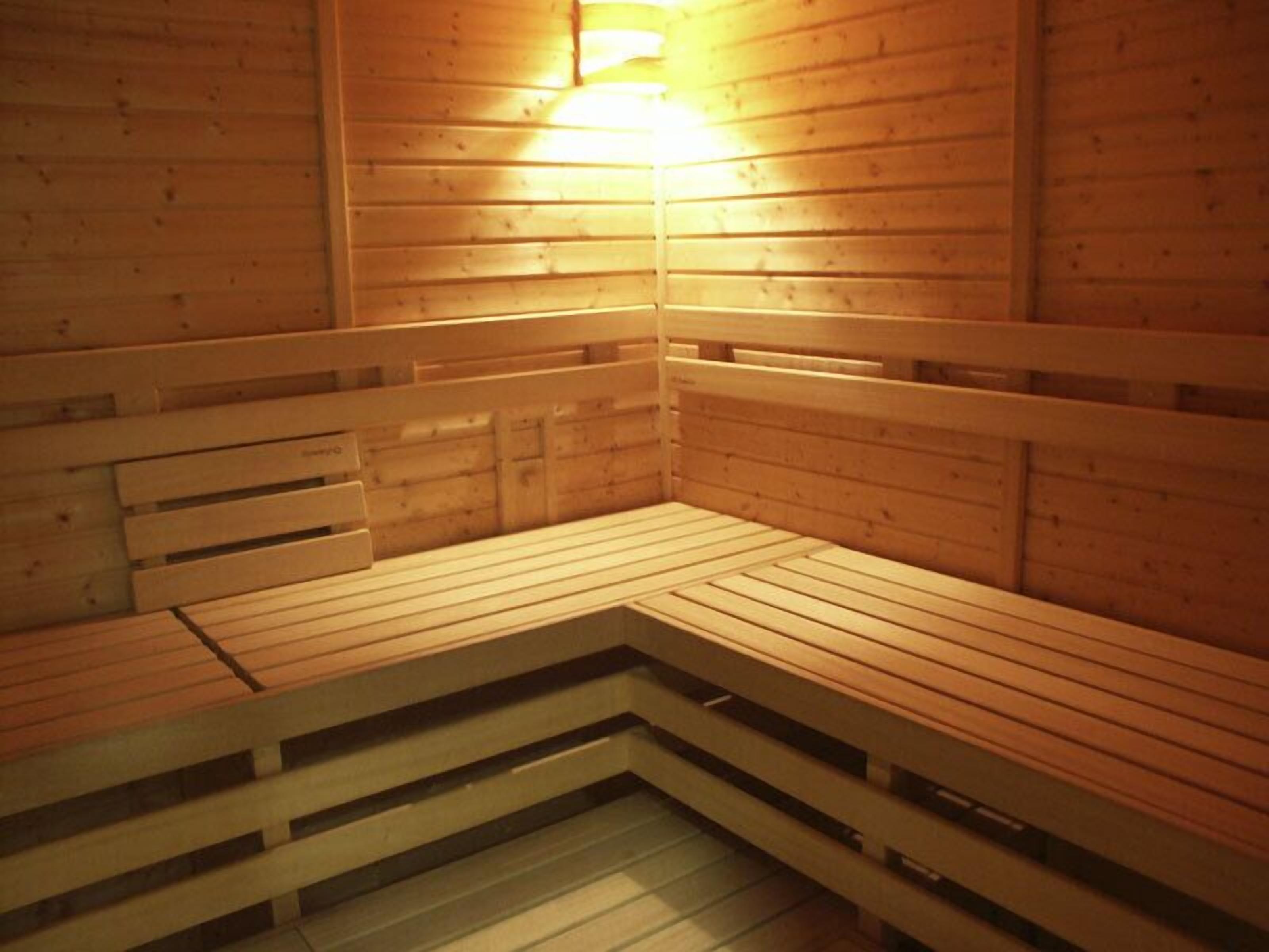 Uma sauna com bancos de madeira e um acessório de iluminação na parede.