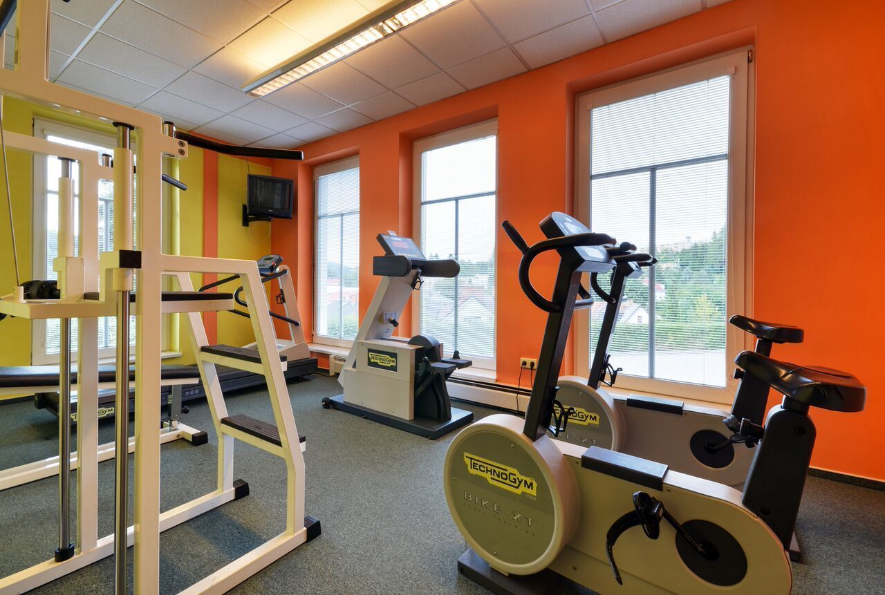 A gym with cardio machines, weightlifting equipment, and large windows.