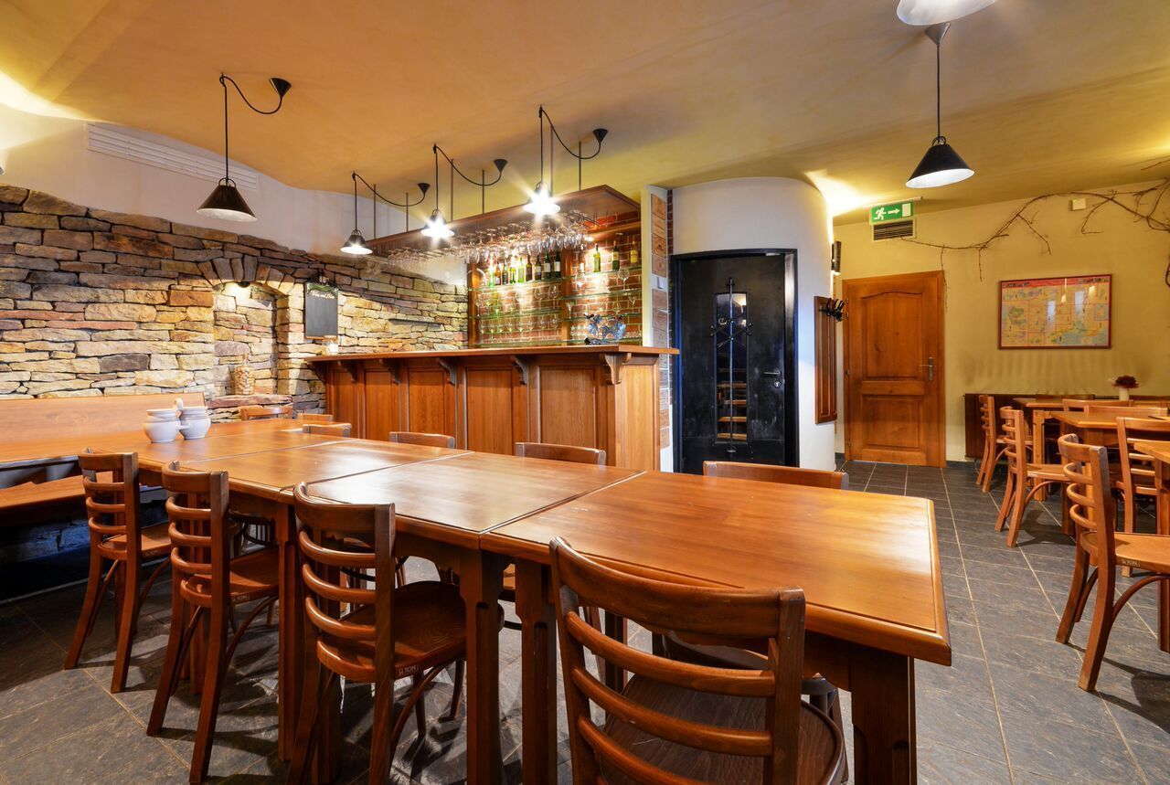 Un restaurant avec un mur en pierre, un bar en bois et de nombreuses tables et chaises.