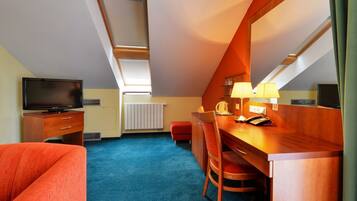Une chambre d’hôtel équipée d’une télévision, d’un bureau avec un téléphone, d’une chaise et d’un canapé rouge.