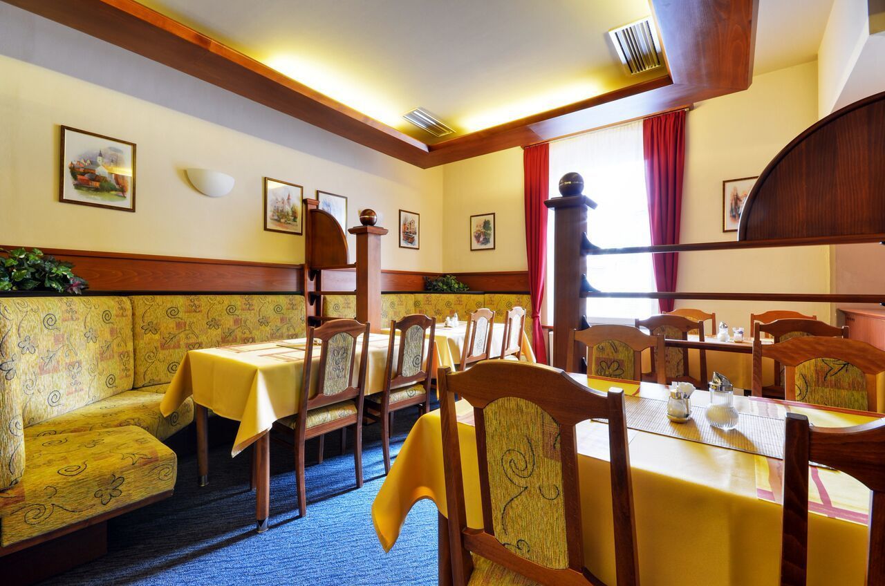 A dining area with wooden furniture, yellow tablecloths, and framed pictures on the walls.