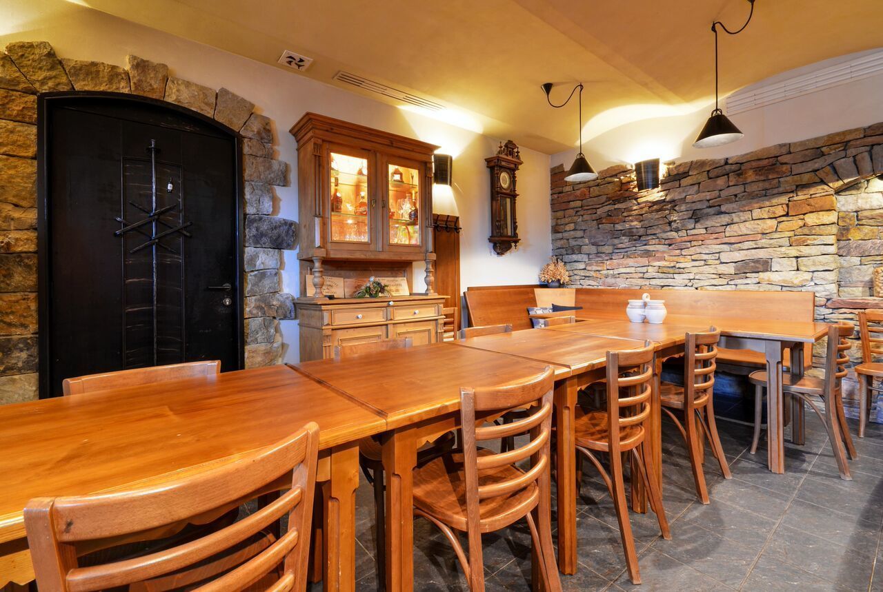A dining area with a wooden table and chairs, a black door, a stone wall, and a wooden cabinet with glass doors.