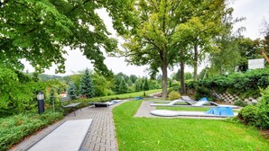 A park with a paved walkway, benches, and a small water feature. - Hotel Filipinum (Jablonne nad Orlici)