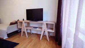 A room with a wooden TV stand, a sofa, and a small table.