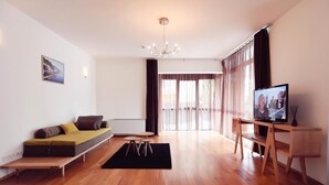 A modern living room with a sofa, a television, and a dining area.