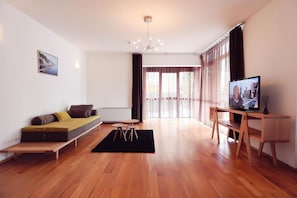 A modern living room with a sofa, a television, and a dining area.