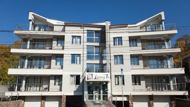 A multi-story hotel with a central entrance, balconies on each floor, and a clear sky.
