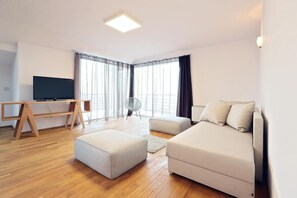 Una sala de estar moderna con un televisor de pantalla plana, un escritorio de madera y un sofá.