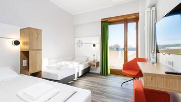 Habitación de hotel con cama, escritorio, silla, ventana con vista y cortina verde.