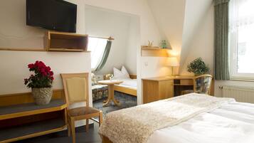 A hotel room with a bed, a desk, a chair, a TV, and a window with curtains.