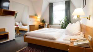 Ein Hotelzimmer mit Bett, Nachttisch, Lampe und Telefon.