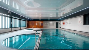 Una piscina interior con agua cristalina, suelo de baldosas y pared divisoria de madera.