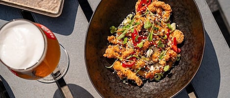 A table with two plates of food, a glass of beer, and a menu.