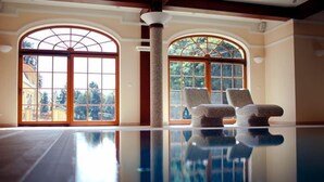 A spacious indoor area with a reflective floor, two large arched windows, and two stone chairs. - Pałac w Rymaniu (Ryman)