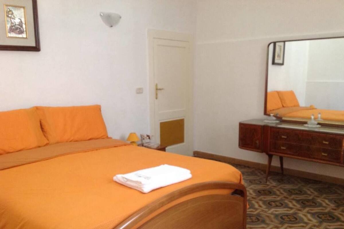 Una habitación de hotel con cama, cómoda, espejo y puerta.