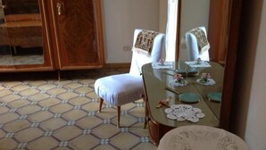 Una habitación con piso estampado, una mesa de comedor con mantel de encaje y una silla con una manta.